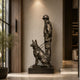 Monumental Soldier and German Shepherd Bronze Sculpture by Giant Sculptures on a dark plinth in a modern entryway with olive tree and wood panelling.