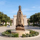 Monumental Classical Our Lady of Fatima Bronze Statue by Giant Sculptures, 400cm figure in prayer with crown on a cloud base, set in a plaza flowerbed.