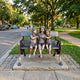Large Traditional Children on Bench Bronze Sculpture by Giant Sculptures showing three barefoot children with a bird on an ornate bench in a tree-lined park.