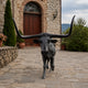 Life-Size Traditional Texas Longhorn Bull Bronze Sculpture by Giant Sculptures, front view on cobblestone driveway before a stone building with arched wooden door.
