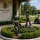 Life-Size Children Baseball Players Bronze Sculpture Set by Giant Sculptures, showing a pitcher and batter in a hedged garden bed outside Greenfield Golf Club.