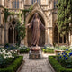 Life-Size Classical Standing Virgin Mary Bronze Statue by Giant Sculptures, arms outstretched on an AVE MARIA granite pedestal in a Gothic cathedral rose garden.