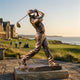 Life-Size Traditional Male Golfer Bronze Sculpture, 220cm, mid-swing follow-through pose on a stone base, displayed outdoors on a golf course overlooking the coastline.