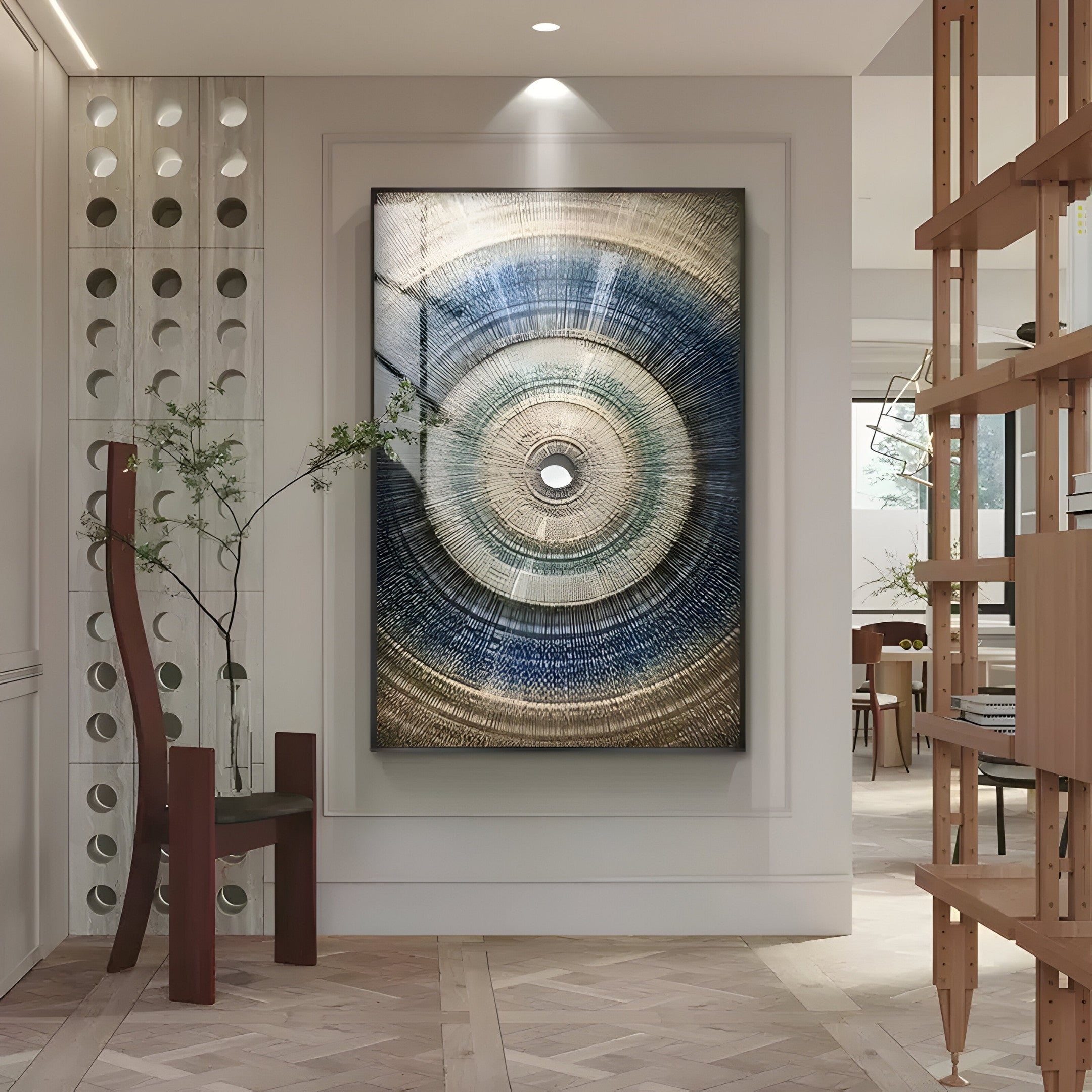 A modern living room showcases the Auralis Blue Gradient Concentric Circular Cardboard Craft Wall Art by Giant Sculptures. Nearby, a minimalist chair and potted plant complement the decor, while sleek shelving and natural light enhance the contemporary atmosphere.