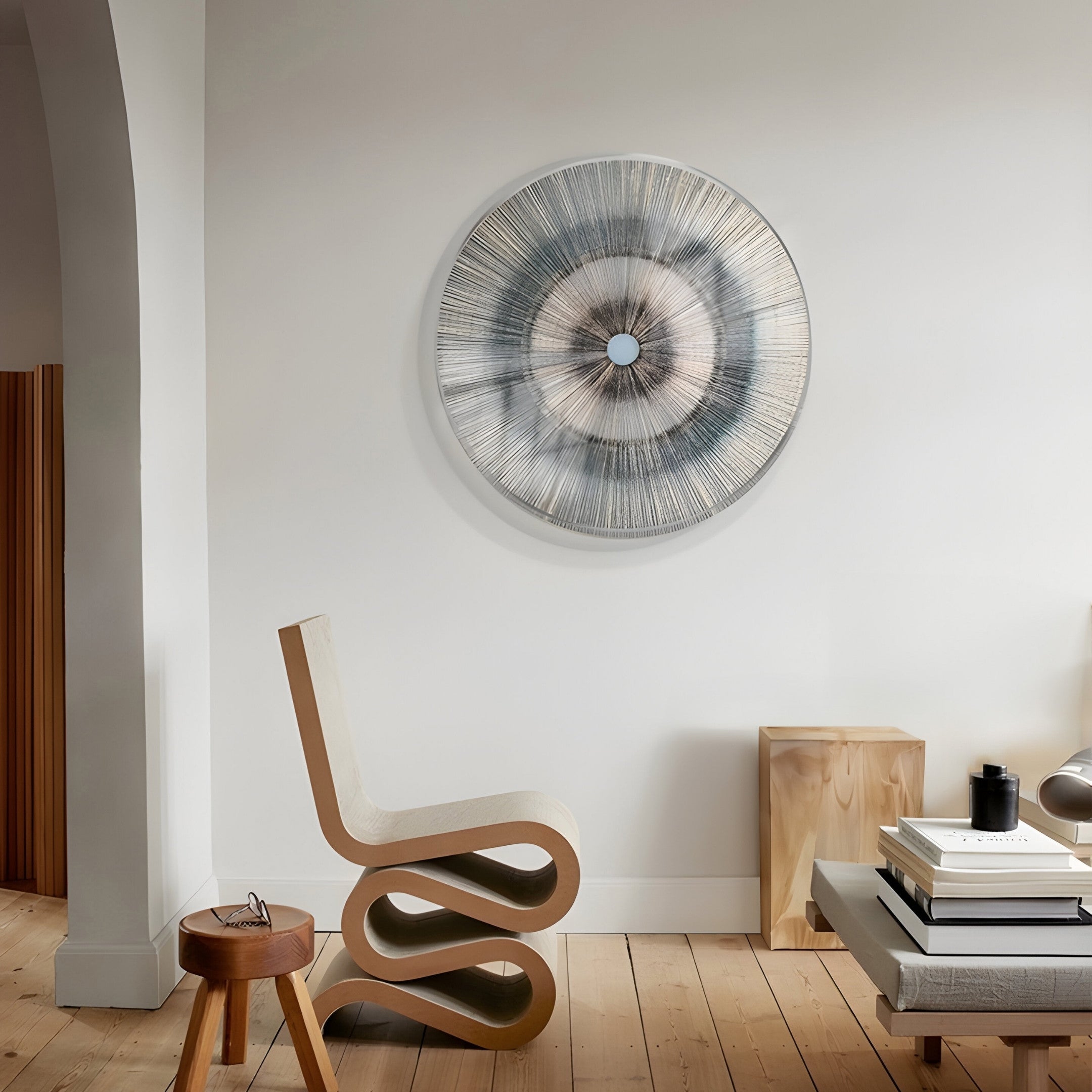 A modern living room showcases a wavy wooden chair and a striking Giant Sculptures Oculis Aqua Luminous Circular Handmade 3D Paper Wall Art in neutral tones. A wooden side table, stacked books, and a lamp adorn the simple floor beneath an archway.