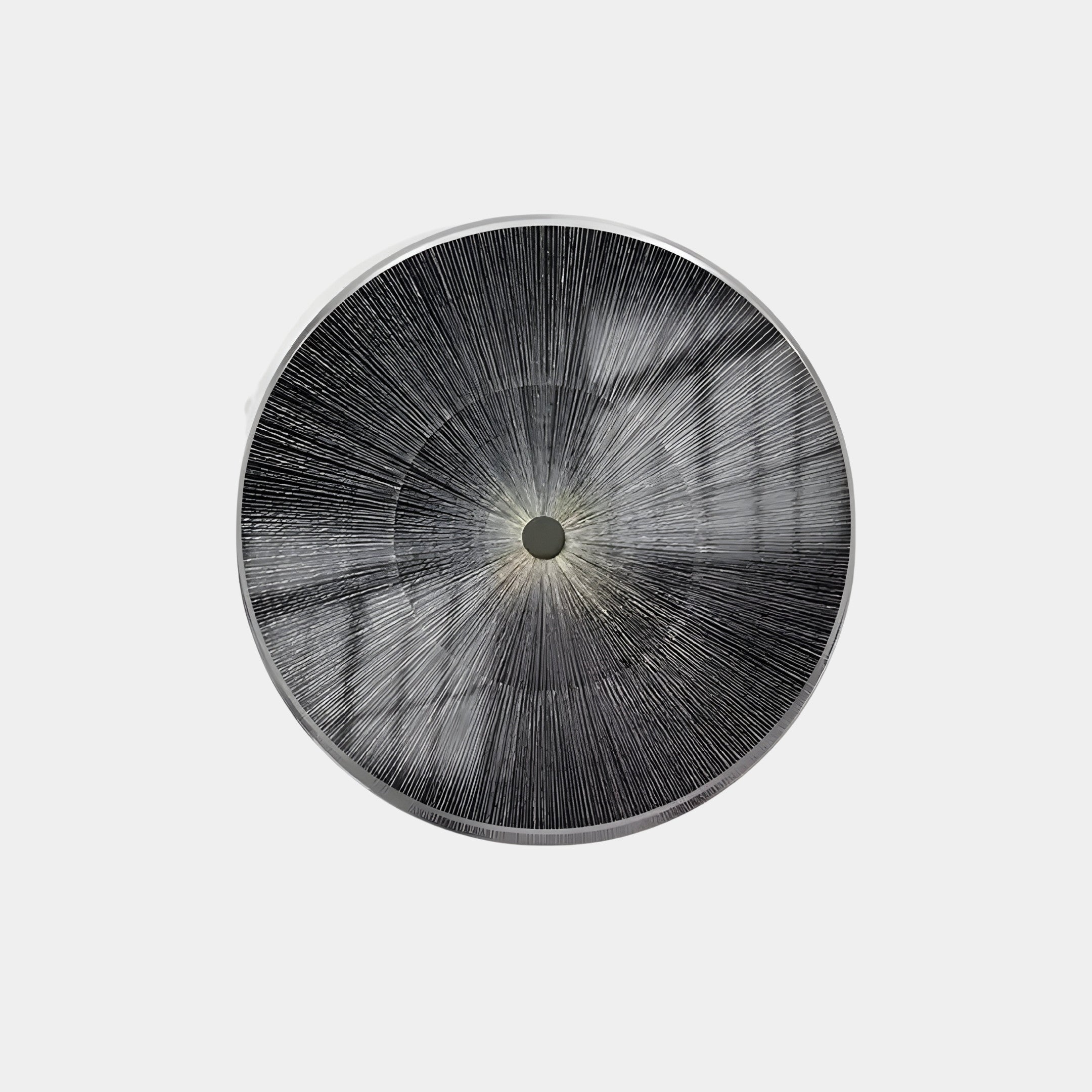 The Oculis Dark Monochrome Circular Handmade 3D Paper Wall Art by Giant Sculptures features radial black lines merging at the center, creating a starburst effect. Its reflective quality suggests a metallic texture, and the plain white background highlights its striking simplicity.