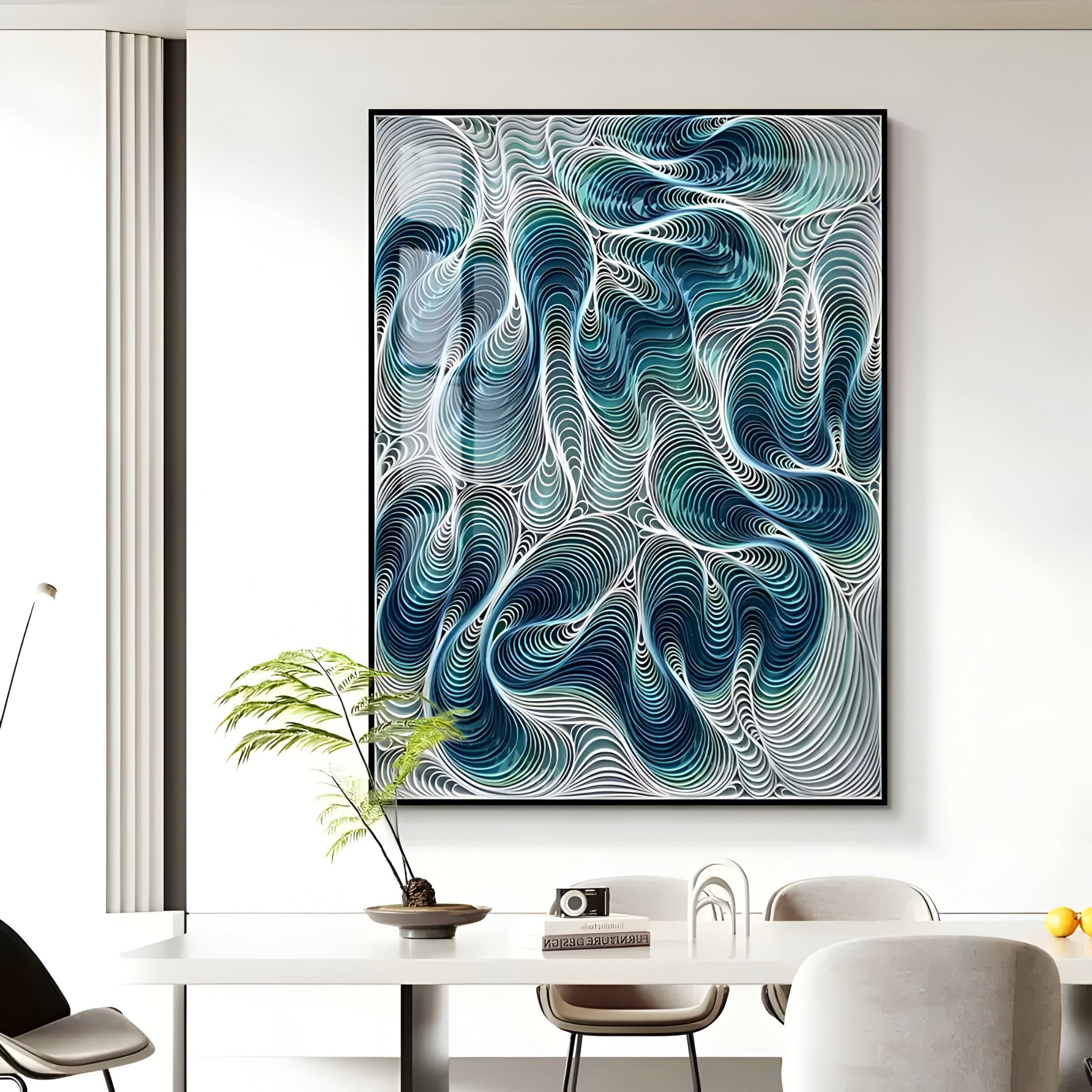 A modern living room features the Filigree Ocean Waves Quilling Paper Wall Art by Giant Sculptures, showcasing swirling blue and white patterns. A sleek white table with a green potted plant and camera is surrounded by neutral-toned chairs as natural light enhances the coastal decor.