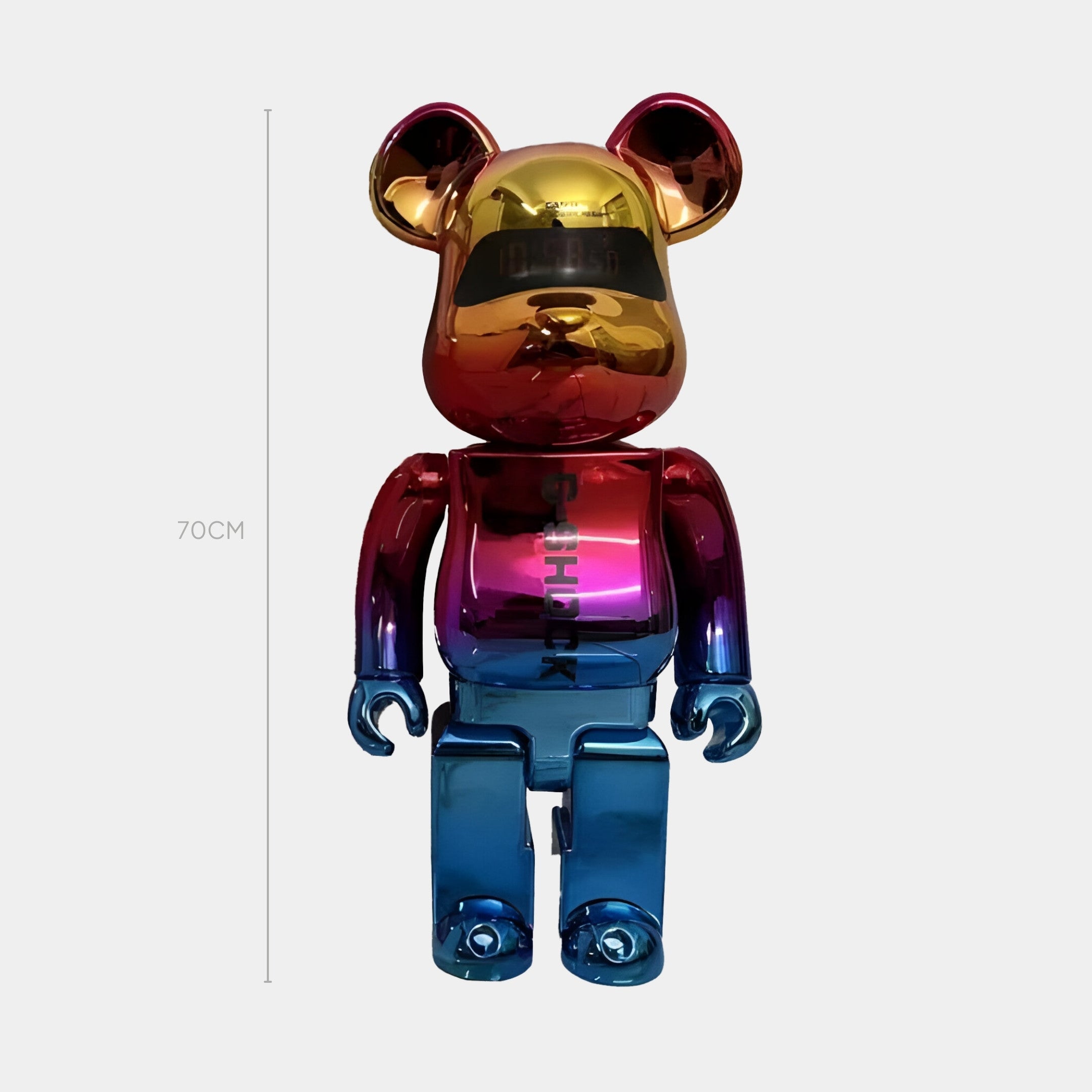 The Giant Sculptures Color Flux Bear Sculpture - 70cm stands upright against a plain light background, displaying its shiny, liquid gradient finish in gold, red, purple, and blue that captures reflective drama from every angle.