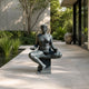 Giant Sculptures Contemporary Seated Nude Female Bronze Sculpture 140cm in cross-legged meditation pose with verdigris patina, on a plinth in a garden courtyard.