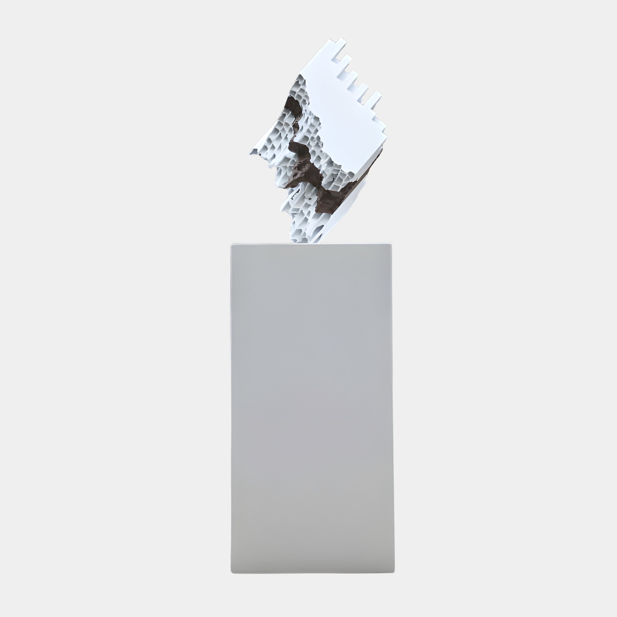 White Abstract Fractured Crystal Form sculpture by Giant Sculptures, a cracked geometric block revealing a porous interior, displayed on a tall grey plinth.