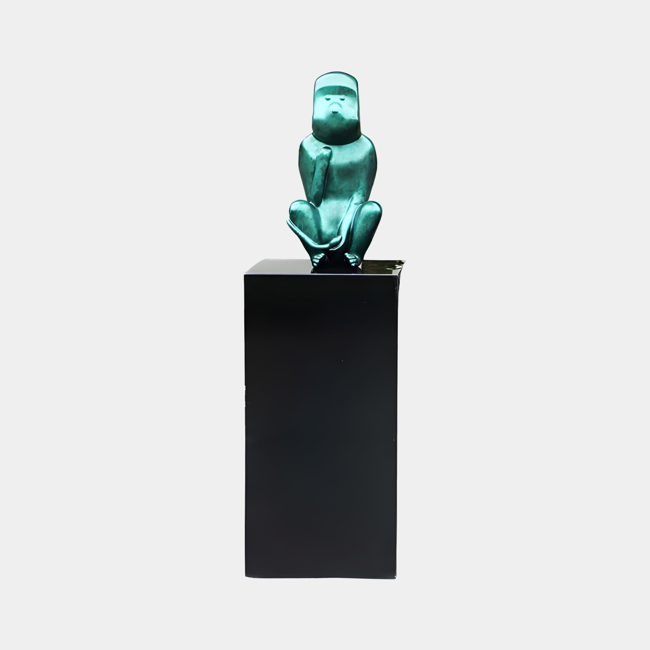 Teal Frog on Black Plinth Sculpture by Giant Sculptures, a crouching metallic teal-green resin frog hugging its knees atop a tall black plinth against a plain background.