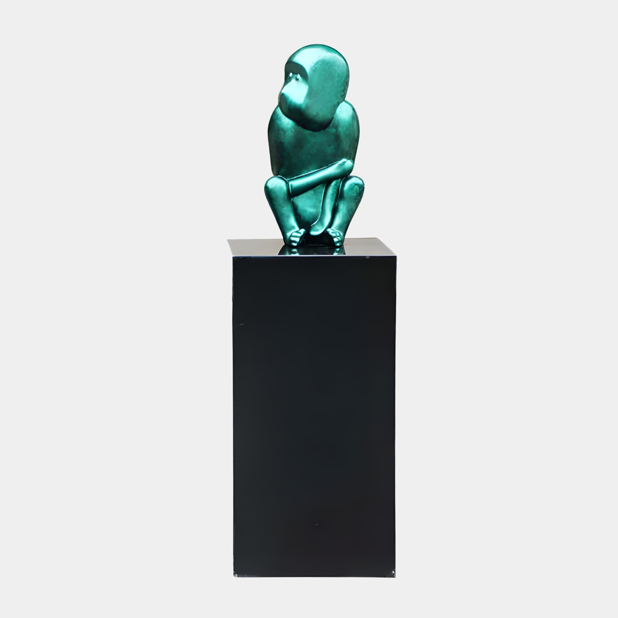 Teal Frog on Black Plinth Sculpture by Giant Sculptures, a metallic green crouching frog hugging its knees atop a tall black plinth against a plain background.