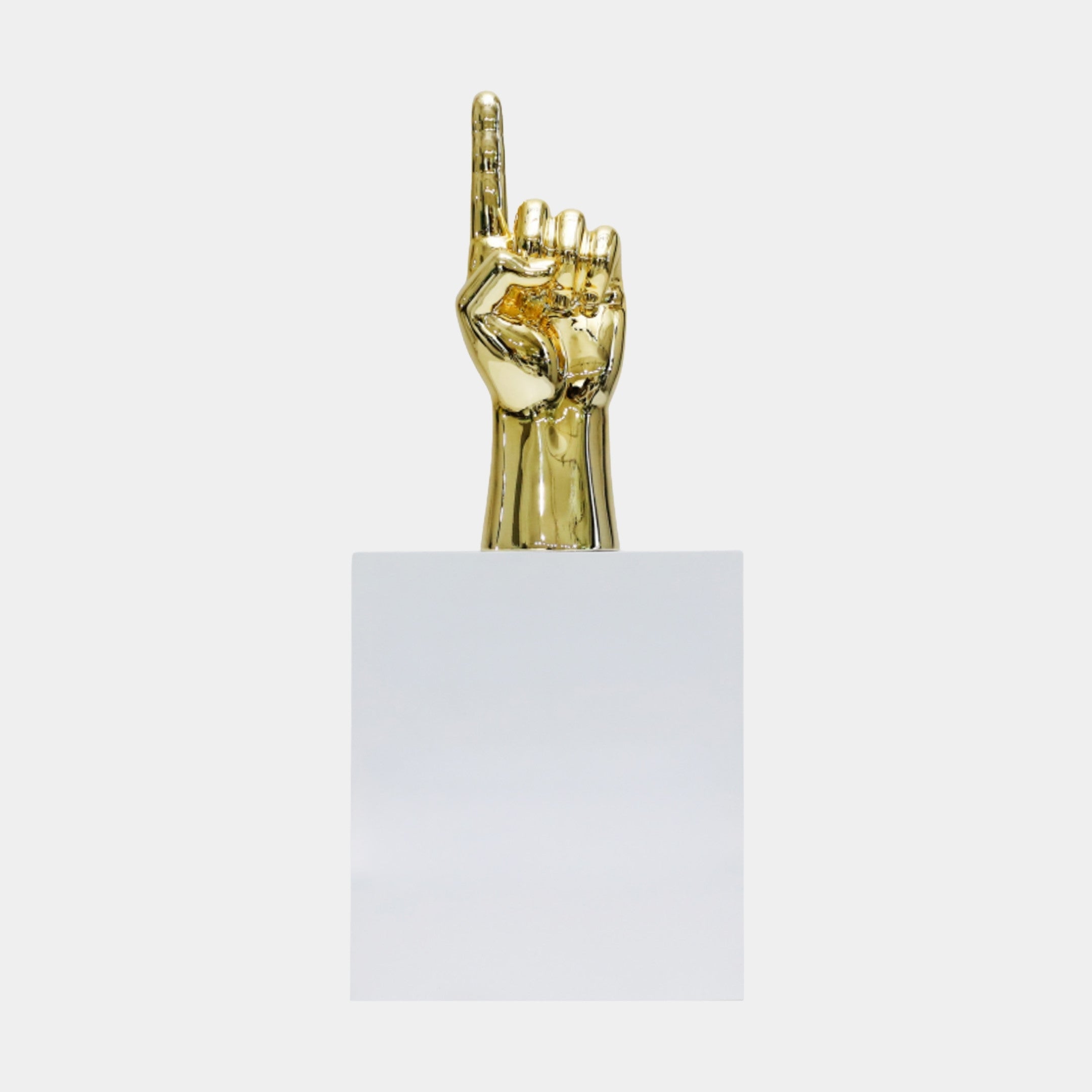 Gold Pointing Hand Sculpture by Giant Sculptures, a polished 3D-printed resin hand with index finger raised skyward, mounted on a white pedestal against a plain background.