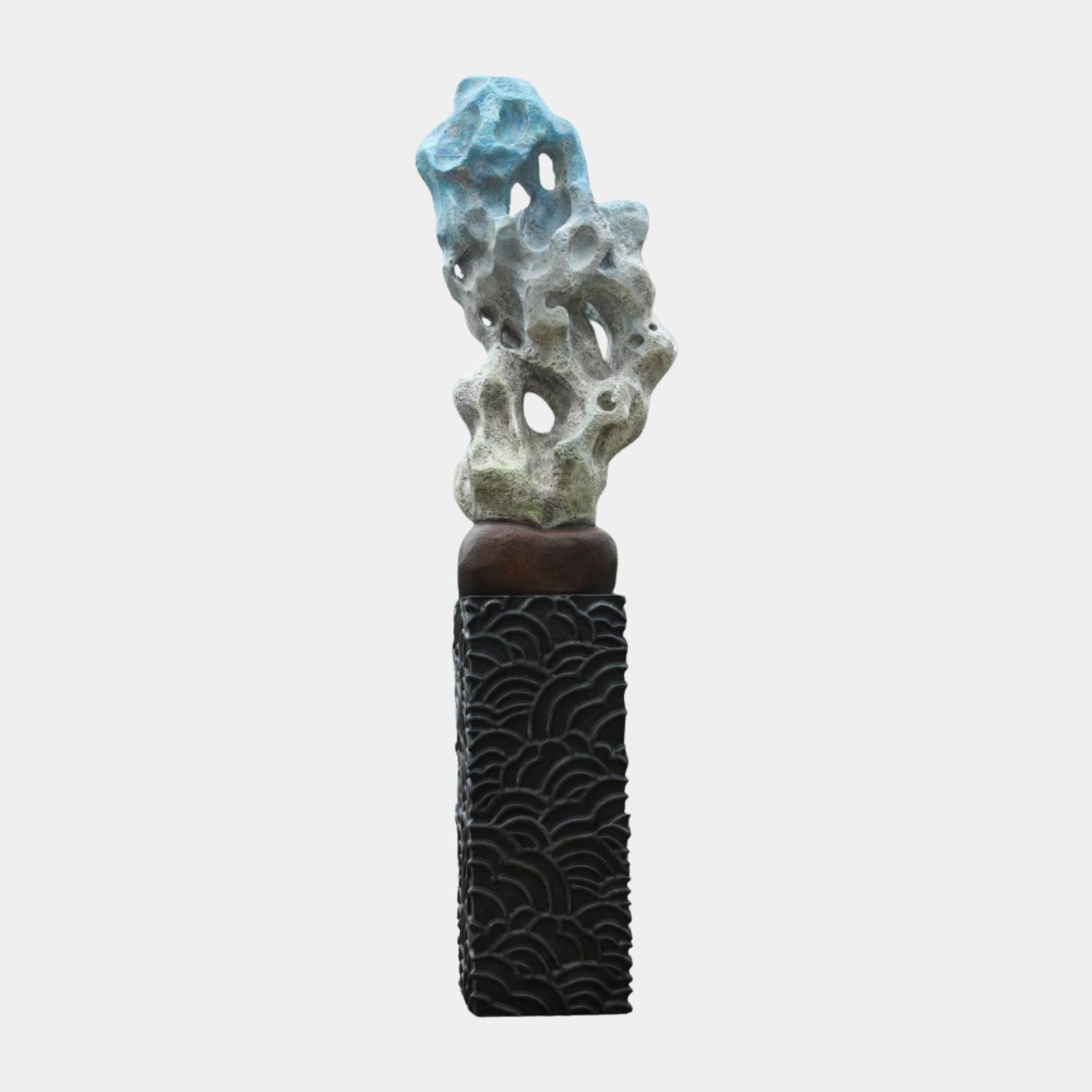 Blue and stone-grey abstract scholar's rock sculpture with pierced, porous form on a black plinth carved with a flowing wave motif, shown on a plain background.