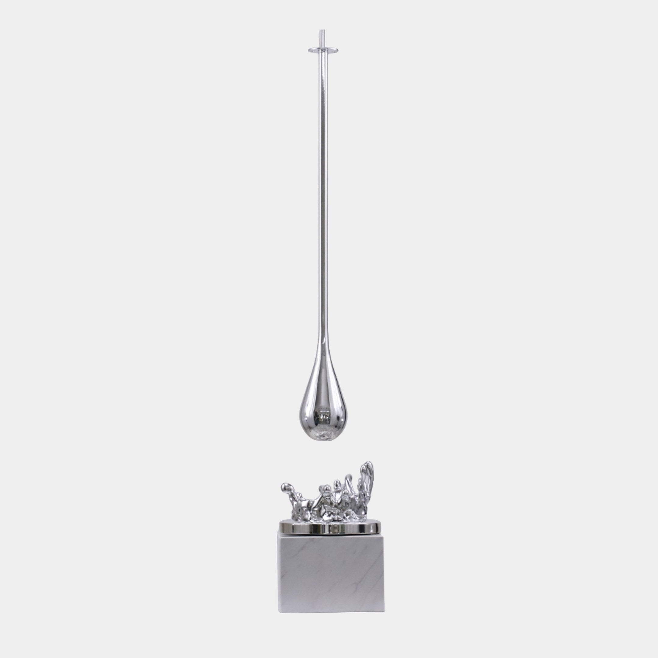 Silver Slender Teardrop Pendant Sculpture by Giant Sculptures, 80cm, showing a chrome teardrop suspended above a splash on a marble base, plain background.