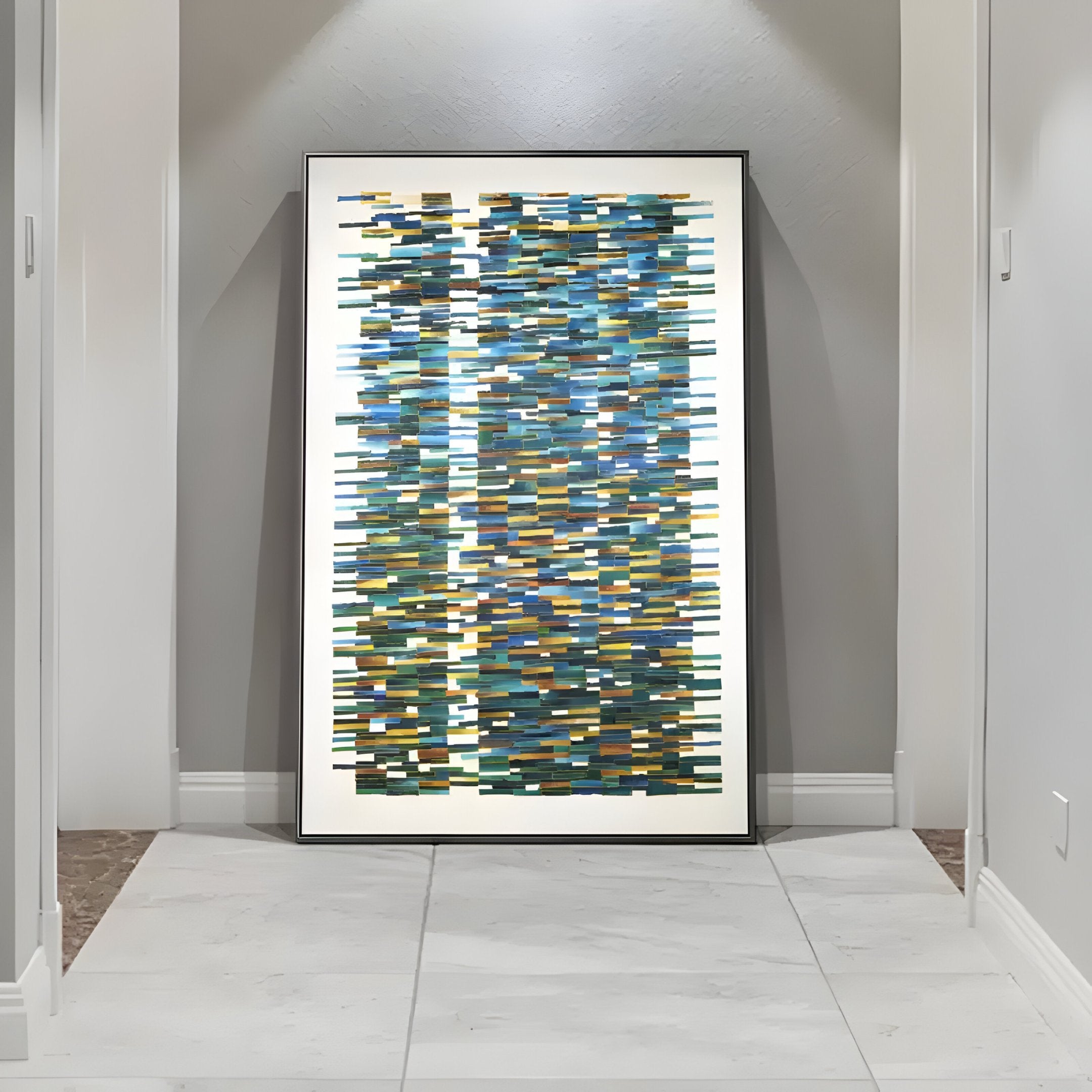 The Timewave Multicoloured Abstract Lines Enamel Wall Art by Giant Sculptures, featuring blue, green, and gold rectangular patterns, leans against a gray wall in a minimalistic hallway with white tiles. This modern luxury piece exudes elegance and style.