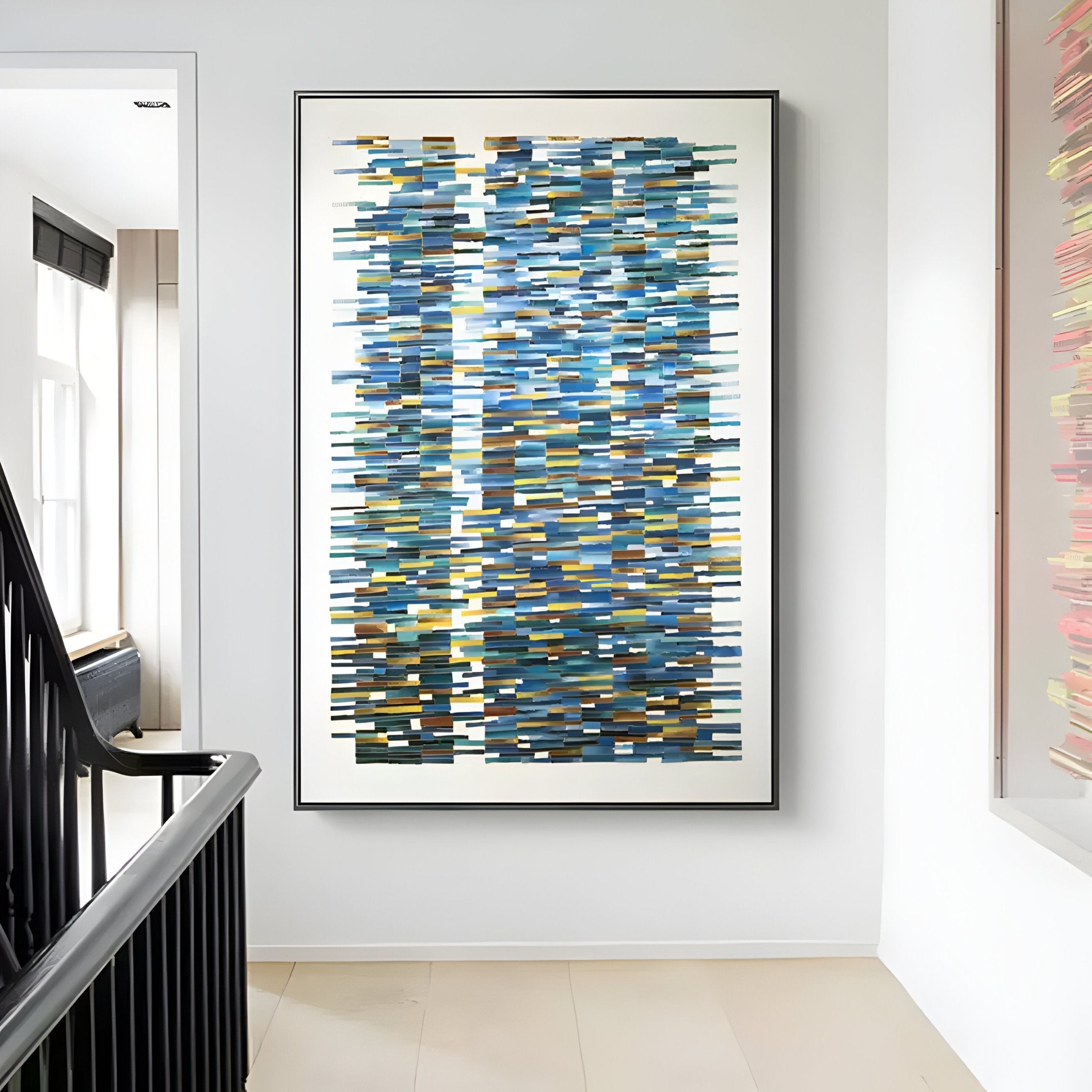 The framed Timewave Vibrant geometric enamel wall art by Giant Sculptures, featuring horizontal stripes in blue, gray, and yellow hues, adorns a white wall in a modern hallway with its contemporary craftsmanship.