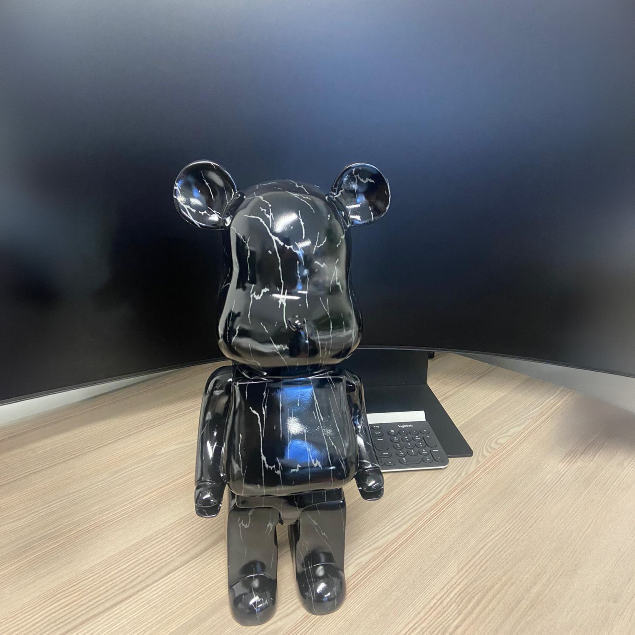 Black Stone Bear Sculpture 50cm by Giant Sculptures with glossy black marbled finish, displayed on a wooden desk beside a keyboard against a dark wall.