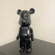 Black Stone Bear Sculpture 50cm by Giant Sculptures with glossy marbled black resin finish, displayed on a dark surface against a white wall.