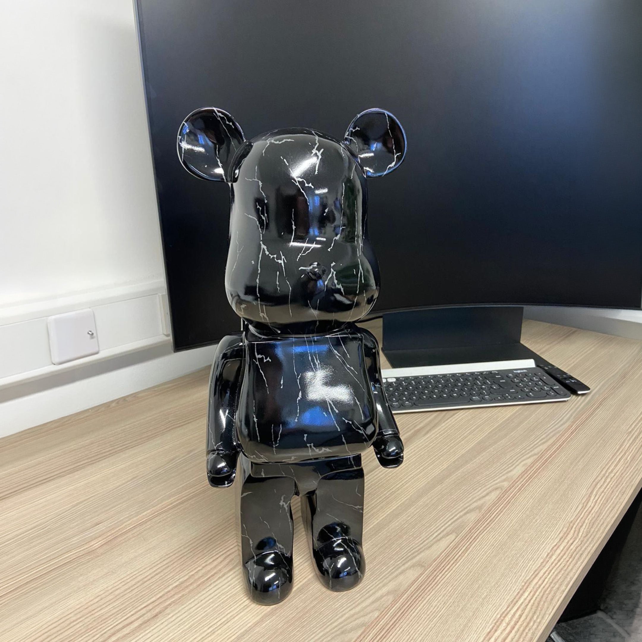 Black Stone Bear Sculpture 50cm by Giant Sculptures with glossy marbled finish, shown on a wooden desk beside a monitor and keyboard.