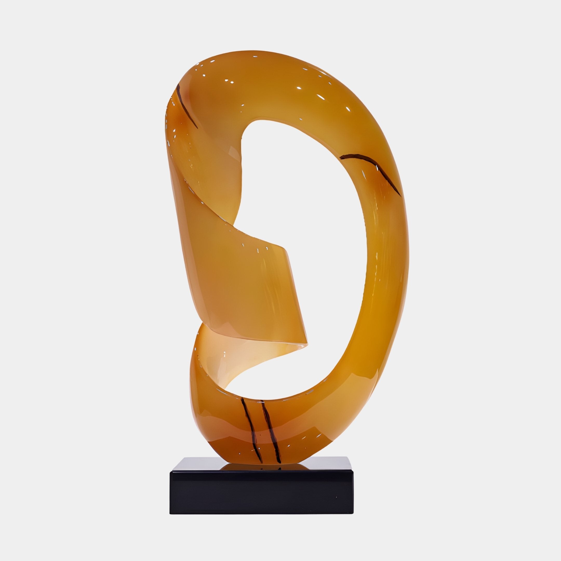 Infinite Loop Amber Abstract Jade Sculpture from Giant Sculptures, a 64cm ribbon-loop form in warm amber with darker streaks, on a black plinth against white.