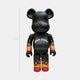 The Flame Black Bear Sculpture - 70cm by Giant Sculptures features a gothic-style logo on its chest and vivid orange-yellow gradient flames on its arms and legs, set against a plain light gray background.