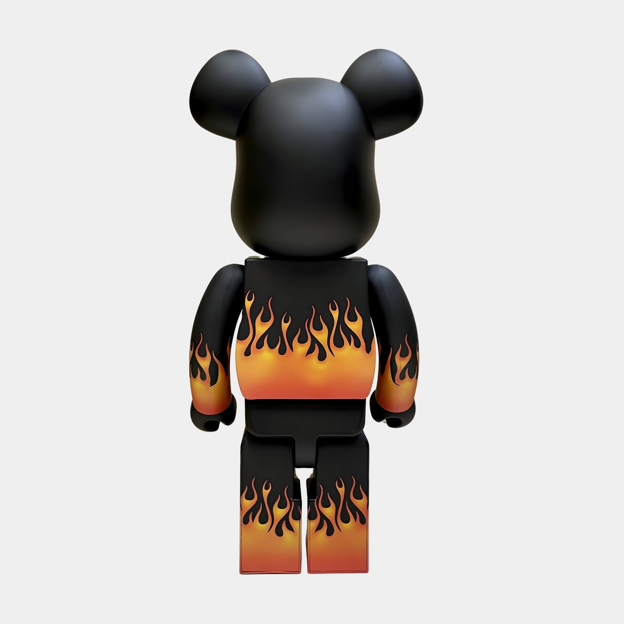 The Giant Sculptures Flame Black Bear Sculpture - 70cm is shown from behind, displaying orange and yellow gradient flames on its arms, torso, and legs against a plain light gray background.