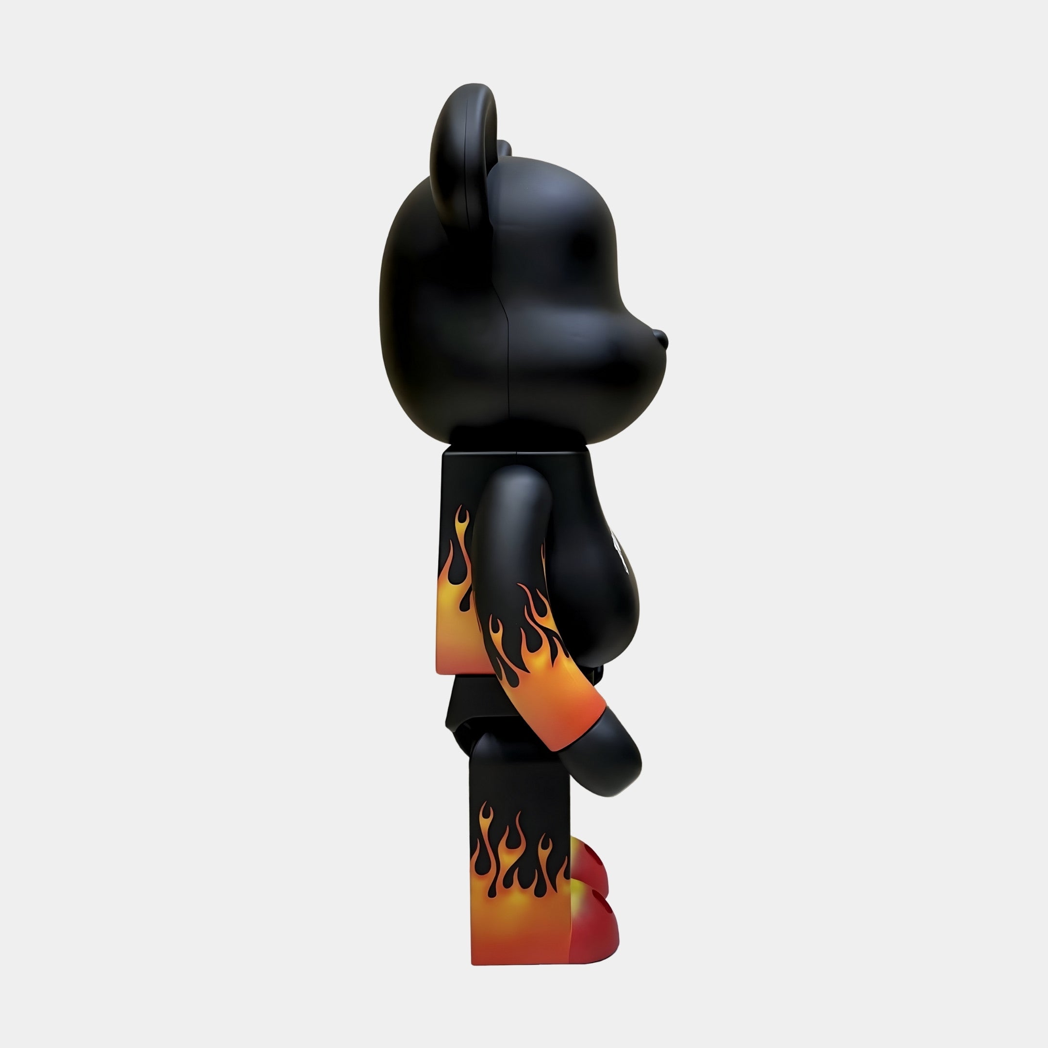 The Flame Black Bear Sculpture - 70cm by Giant Sculptures features a bold profile with orange and yellow gradient flames on its arms and legs, red feet, and stands out against a plain light background.