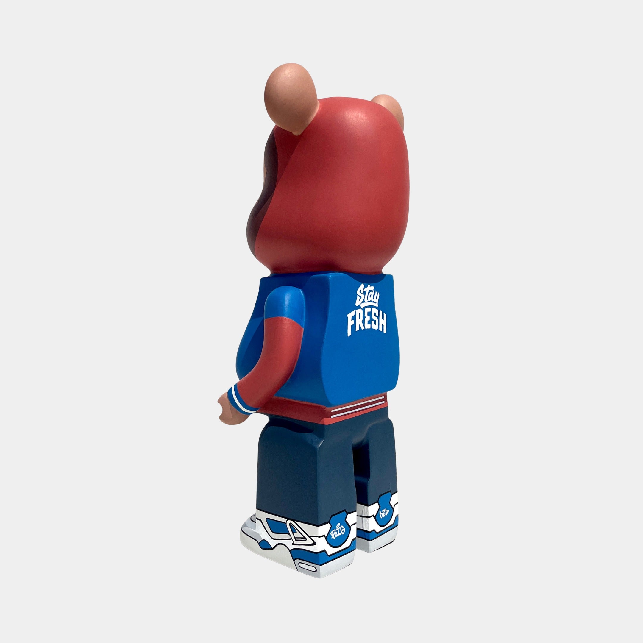 The Fresh Grizz Bear Sculpture - 50cm by Giant Sculptures stands upright in a blue "Stay Fresh" jacket, red hoodie, dark pants, and blue/white sneakers—streetwear art viewed from behind against a plain backdrop. Limited edition.