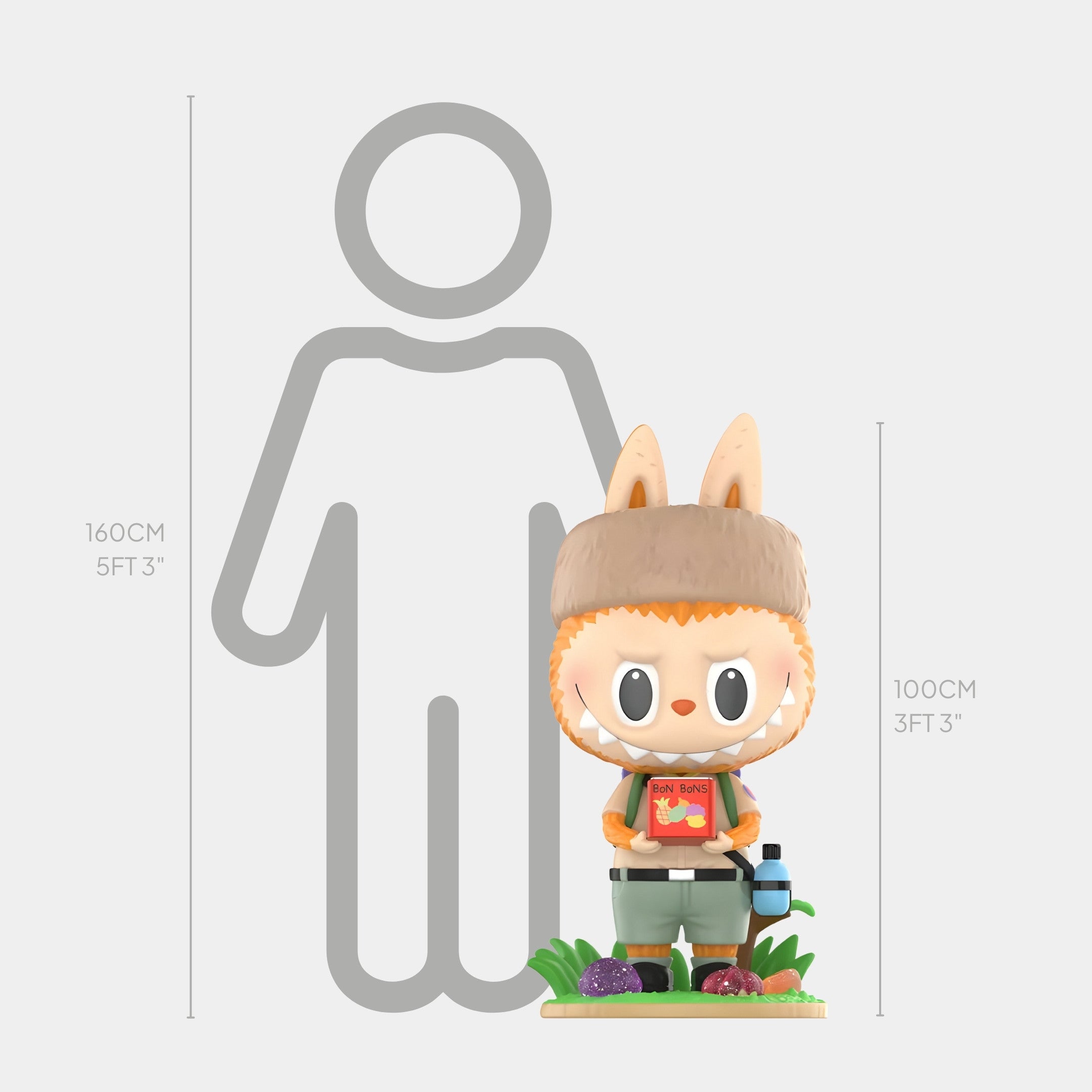 The Fruit Filled Candy Labubu Sculpture - 100cm by Giant Sculptures features animal ears, a furry hat, and a red shirt with a book. This fibreglass piece stands 100cm tall next to a 160cm gray outline of a person for scale.
