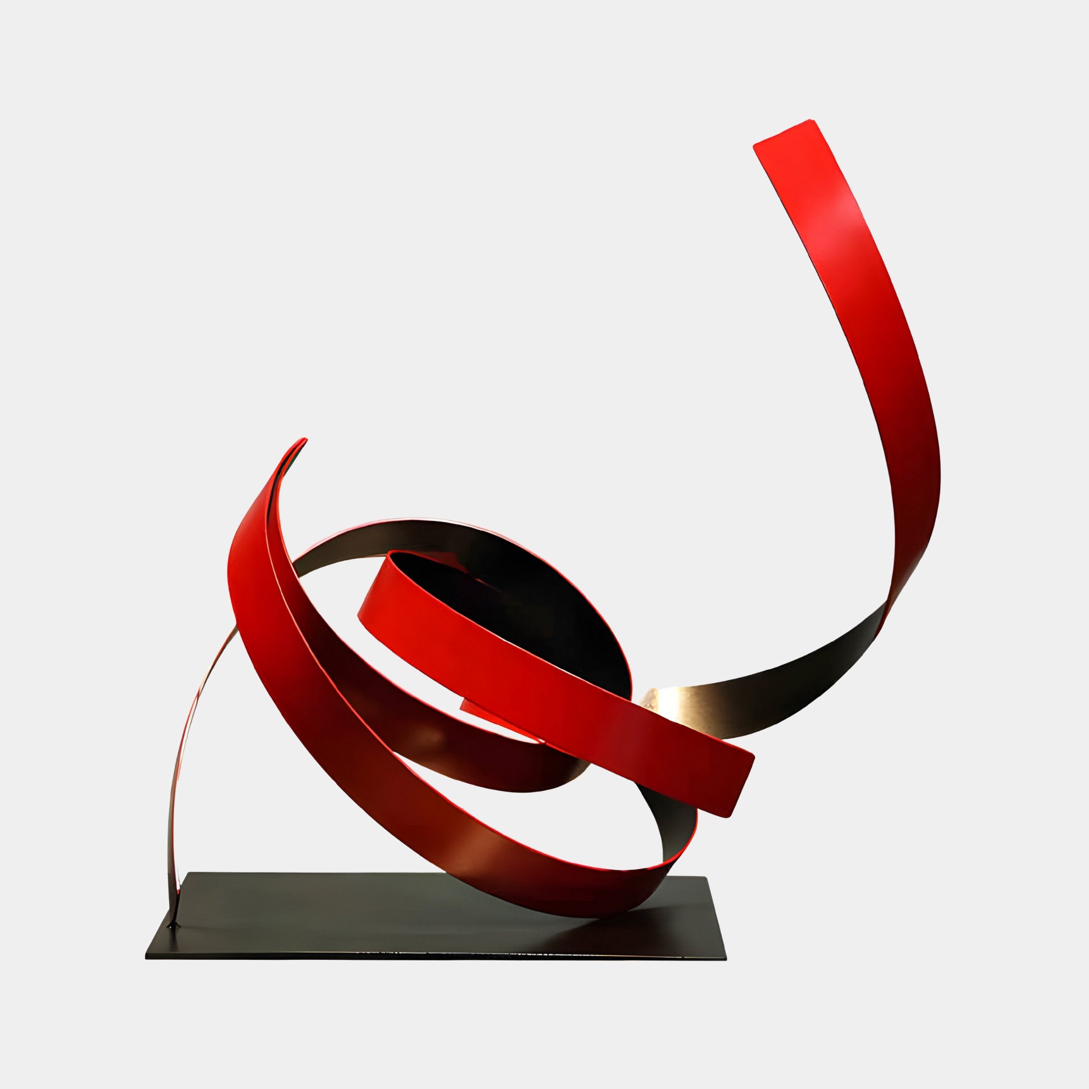 The Ribbon Red V Abstract Steel Sculpture by Giant Sculptures is a modern piece featuring an innovative ribbon design with intertwined, flowing red steel ribbons mounted on a black base. Standing at 59cm, it conveys motion and dynamic energy, with smooth curves creating a striking visual impact against a plain background.