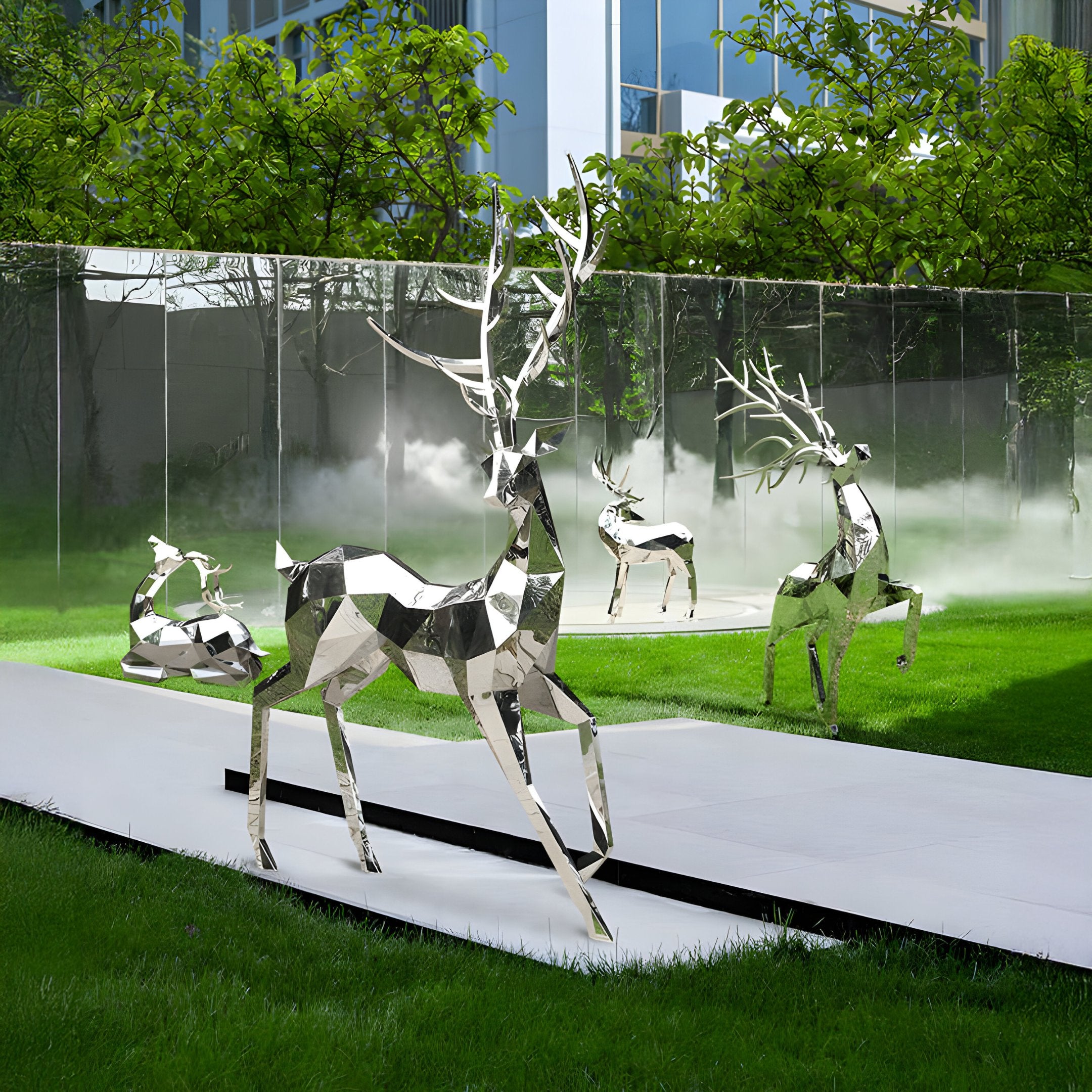 A modern garden features a collection of Noble Deer II Geometric Steel Sculptures from Giant Sculptures, crafted in stainless steel and standing prominently at 198cm tall. These artistic deer sculptures are beautifully positioned on grass with white paths, set against a backdrop of trees and buildings with mist delicately rising near a glass wall. Their varying sizes and poses bring an abstract charm to this enchanting outdoor art scene.