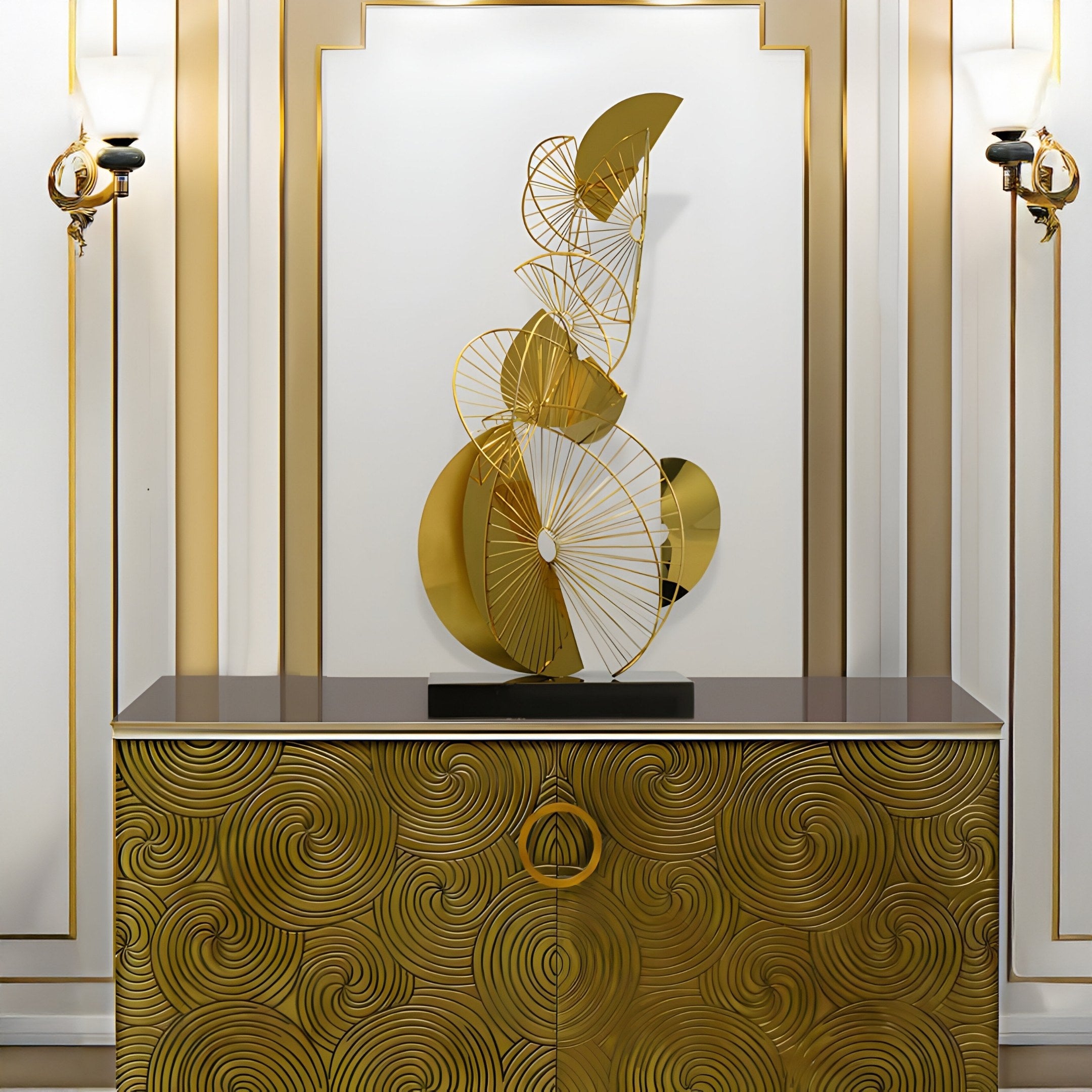 The Celest Abstract Steel Sculpture by Giant Sculptures, a 93cm gold art piece with swirling designs on a black base, is displayed atop a gold-patterned cabinet with intricate spiral motifs. Ideal for modern spaces, its set against an elegant white wall with gold accents and two decorative sconces.