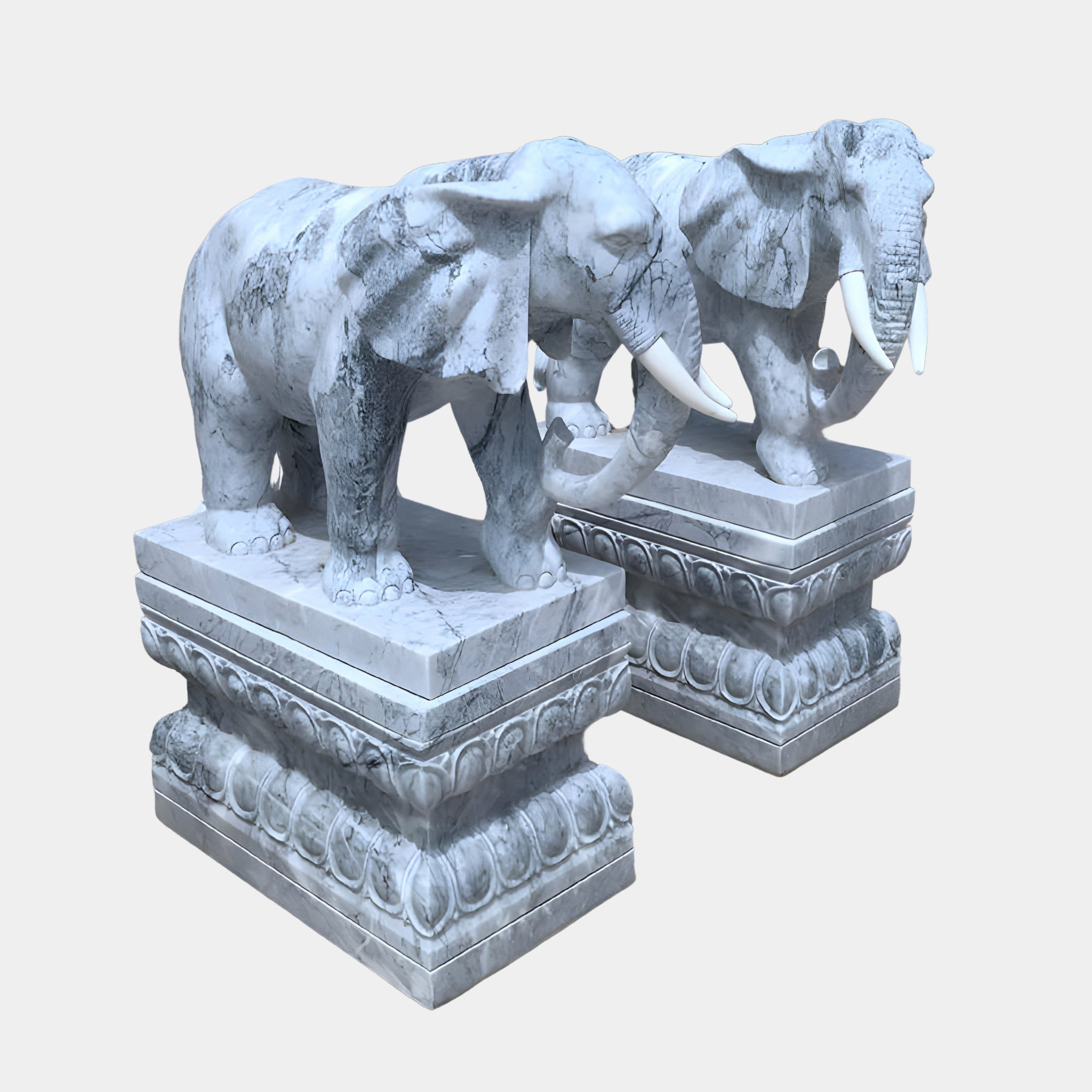 The Elephant Grey Marble Outdoor Sculptures from Giant Sculptures stand on ornate pedestals. At 120cm, these intricately carved statues depict elephants mid-stride with detailed trunks and tusks, offering an imposing and majestic presence.