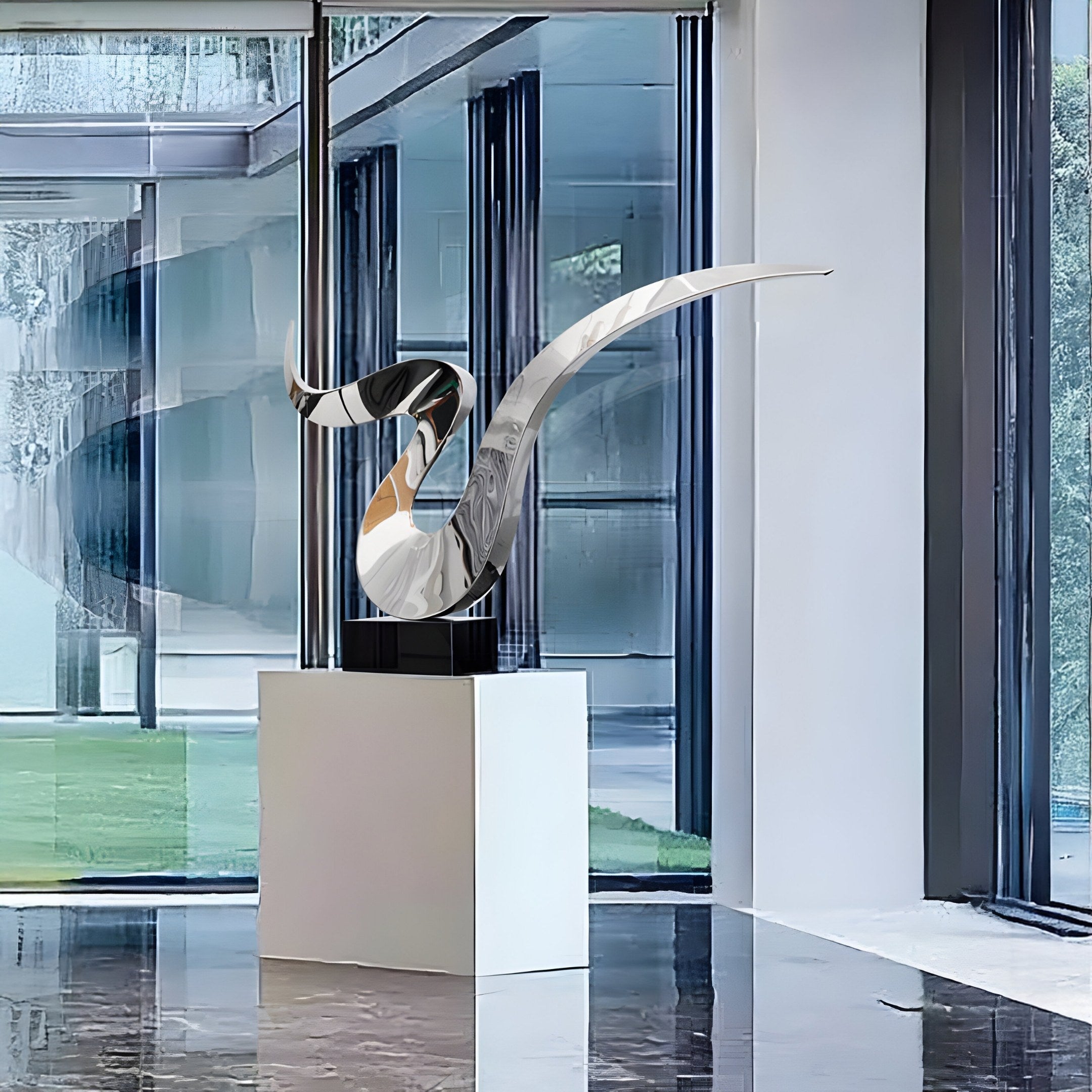 The Whisper Silver Abstract Steel Sculpture by Giant Sculptures, a sleek marvel with curved lines, gleams on a white pedestal indoors. Large glass windows frame the greenery outside, and the reflective marble flooring enhances its modern elegance.