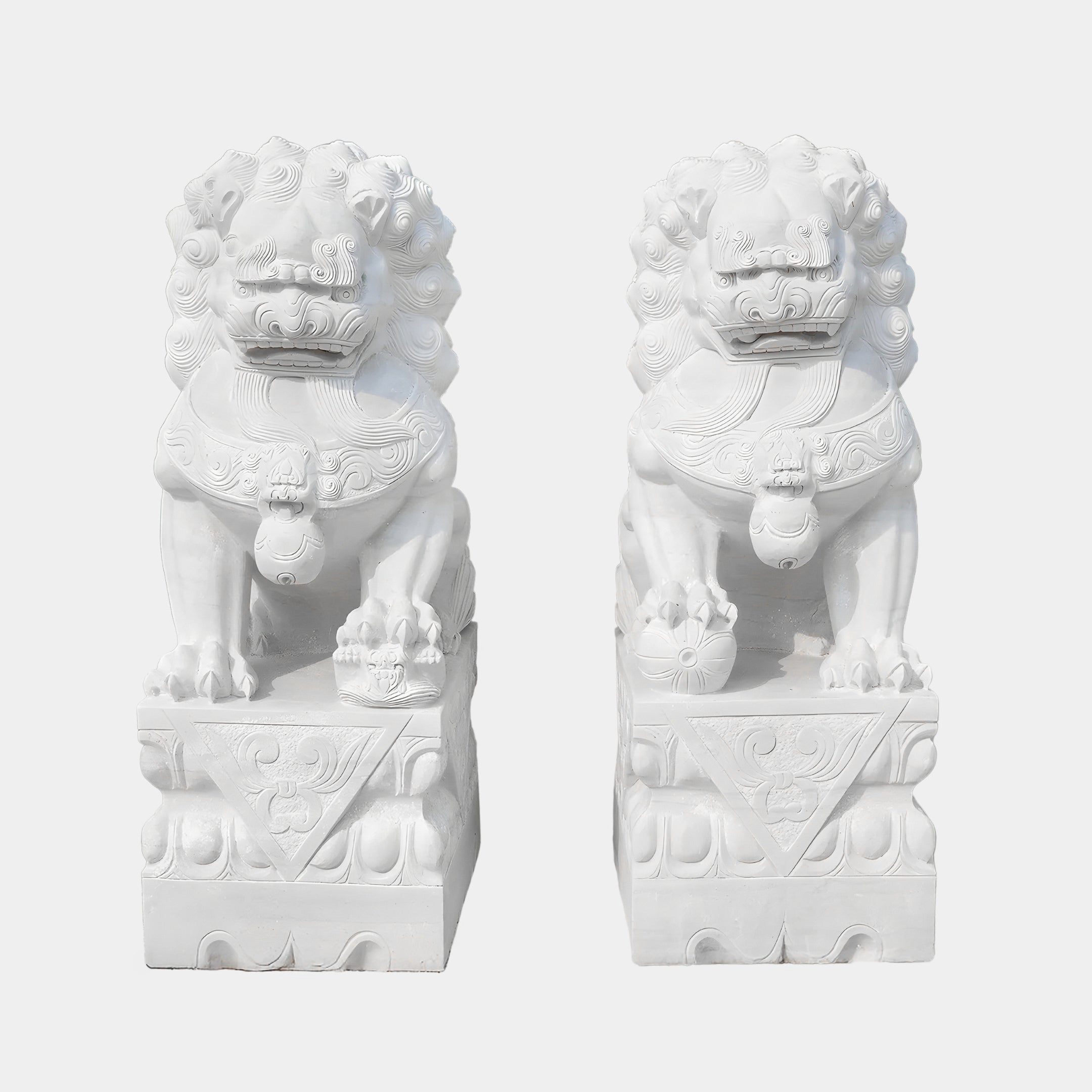 The Chinese Guardian Lion IV Marble Outdoor Sculptures by Giant Sculptures feature two 180cm intricate white marble lions on pedestals. Their detailed curly manes and decorative orbs under their paws enhance the symmetry, with a plain background highlighting these outdoor sculptures.