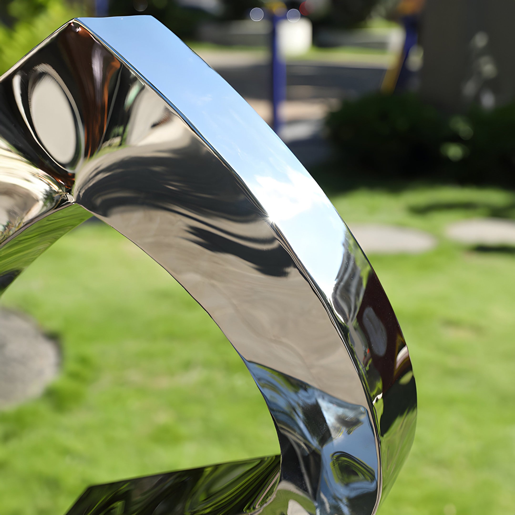 Close-up of Infinity Arc sculpture's polished stainless steel curves, highlighting its mirror-like reflective surface.