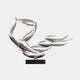 Giant Sculptures Breeze Silver Organic Abstract Steel Sculpture (50cm) features smooth, elongated shapes like leaves or wings in a dynamic swirl on a black rectangular base. Its glossy surface elegantly reflects light and surrounding colors.