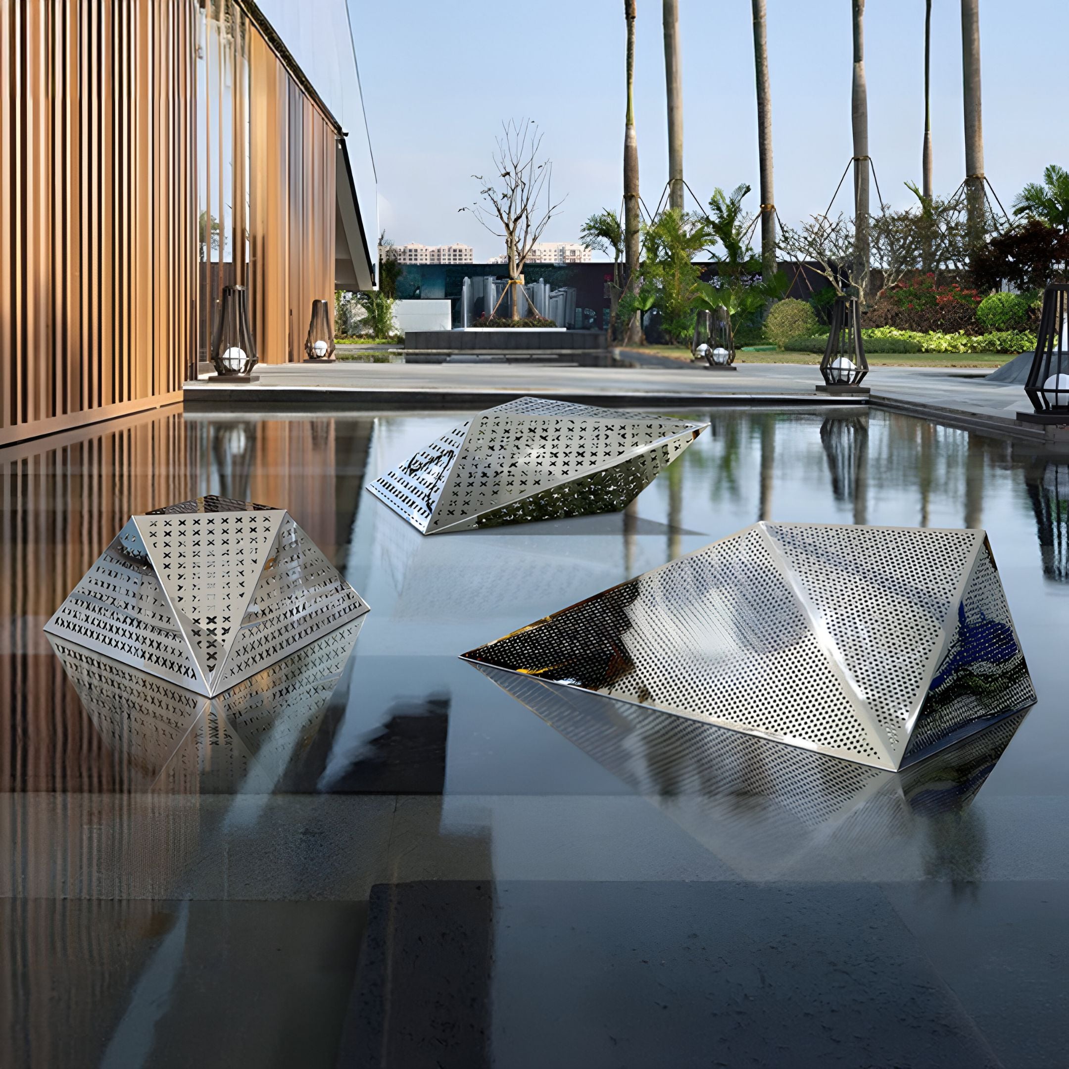 The Edge Geometric Steel Outdoor Sculpture by Giant Sculptures is elegantly placed on a reflective surface outdoors, set against a backdrop of tall palm trees, modern buildings, and lush greenery under a clear sky.