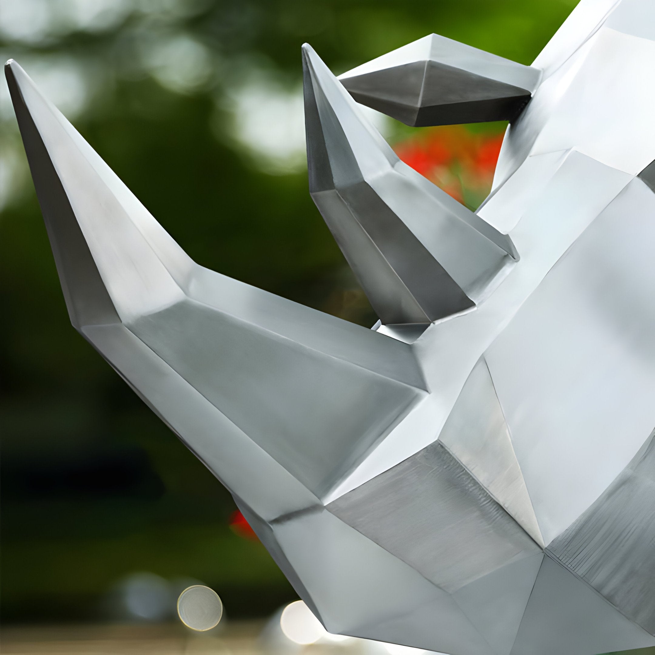 A close-up of the Rhino Geometric Steel Outdoor Sculpture - 210cm by Giant Sculptures showcases its sharp, angular features. The background is a blurred green, hinting at an outdoor display.