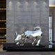 The Toro Bull geometric steel sculpture (193cm) from Giant Sculptures stands indoors against a textured wall. Soft lighting above and decor-filled shelves on the left echo the elegance of outdoor sculptures in contemporary landscapes.