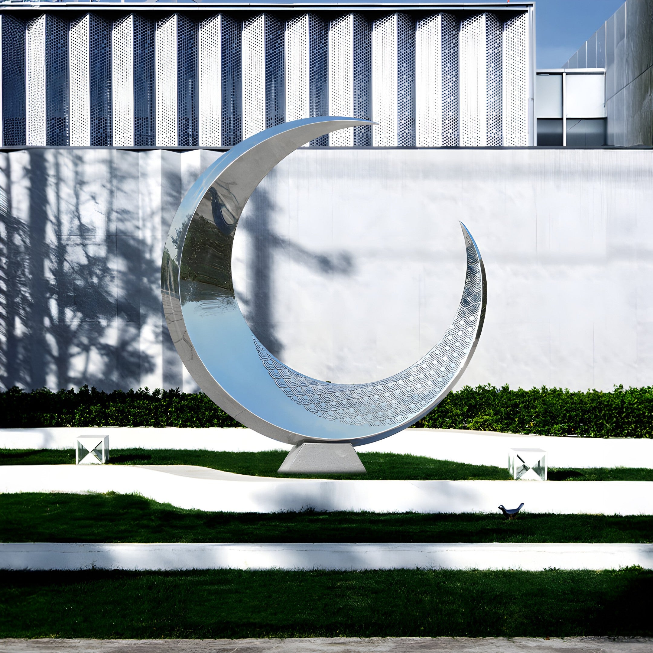 A crescent-shaped stainless steel sculpture placed on a modern terrace, reflecting light and enhancing the architectural surroundings.