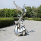 Abstract stainless steel phoenix sculpture in silver finish displayed outdoors.