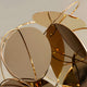 Close-up detail of the golden circular abstract sculpture, showing its shiny reflective surface.