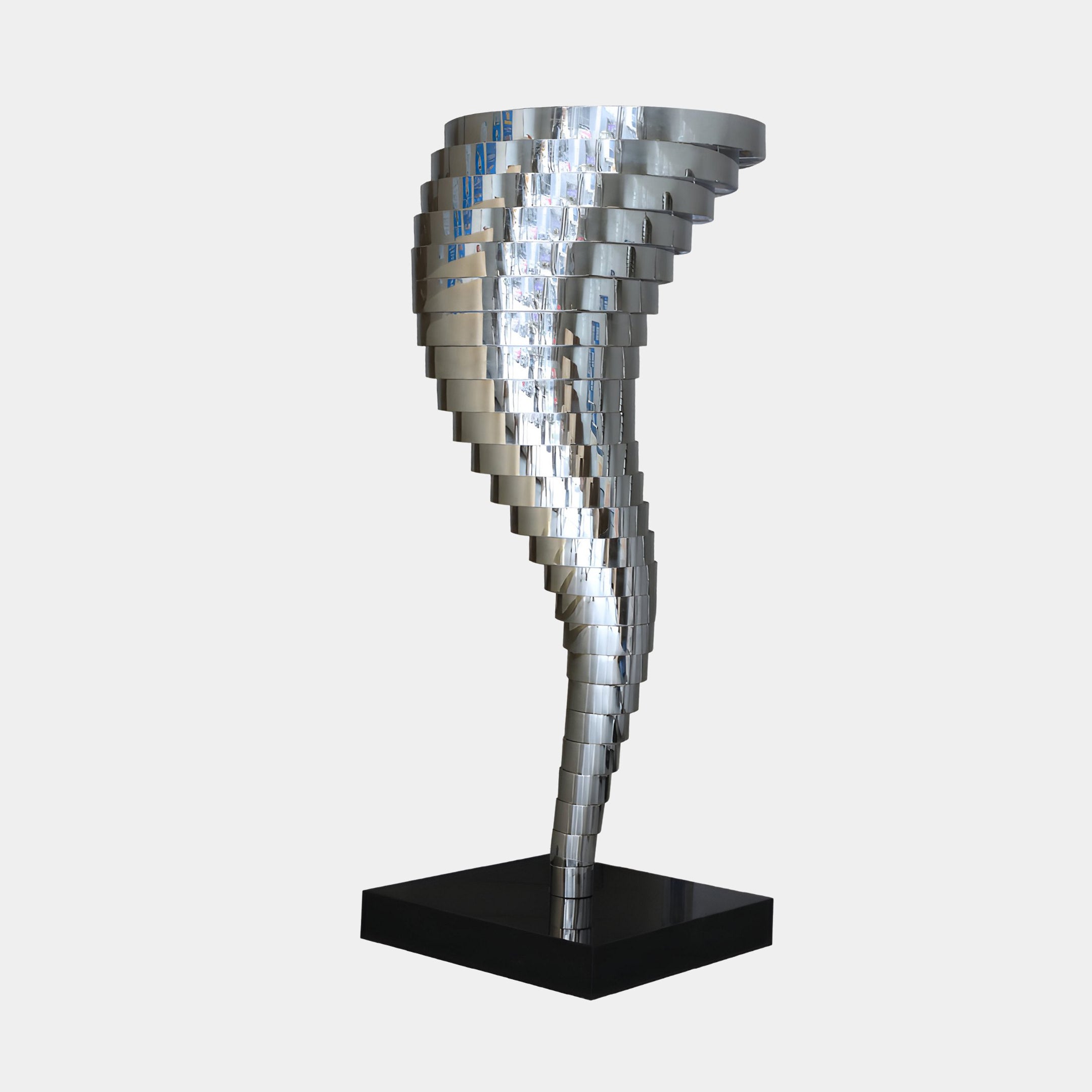 The Vortex Abstract Steel Sculpture - 163cm by Giant Sculptures embodies modern elegance with its beautifully spiraling metallic rectangular plates. Constructed from stainless steel, this dynamic form is set on a sleek black base against a simple white backdrop.