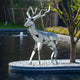 Sculpture positioned near a water feature, reflecting the surrounding environment.