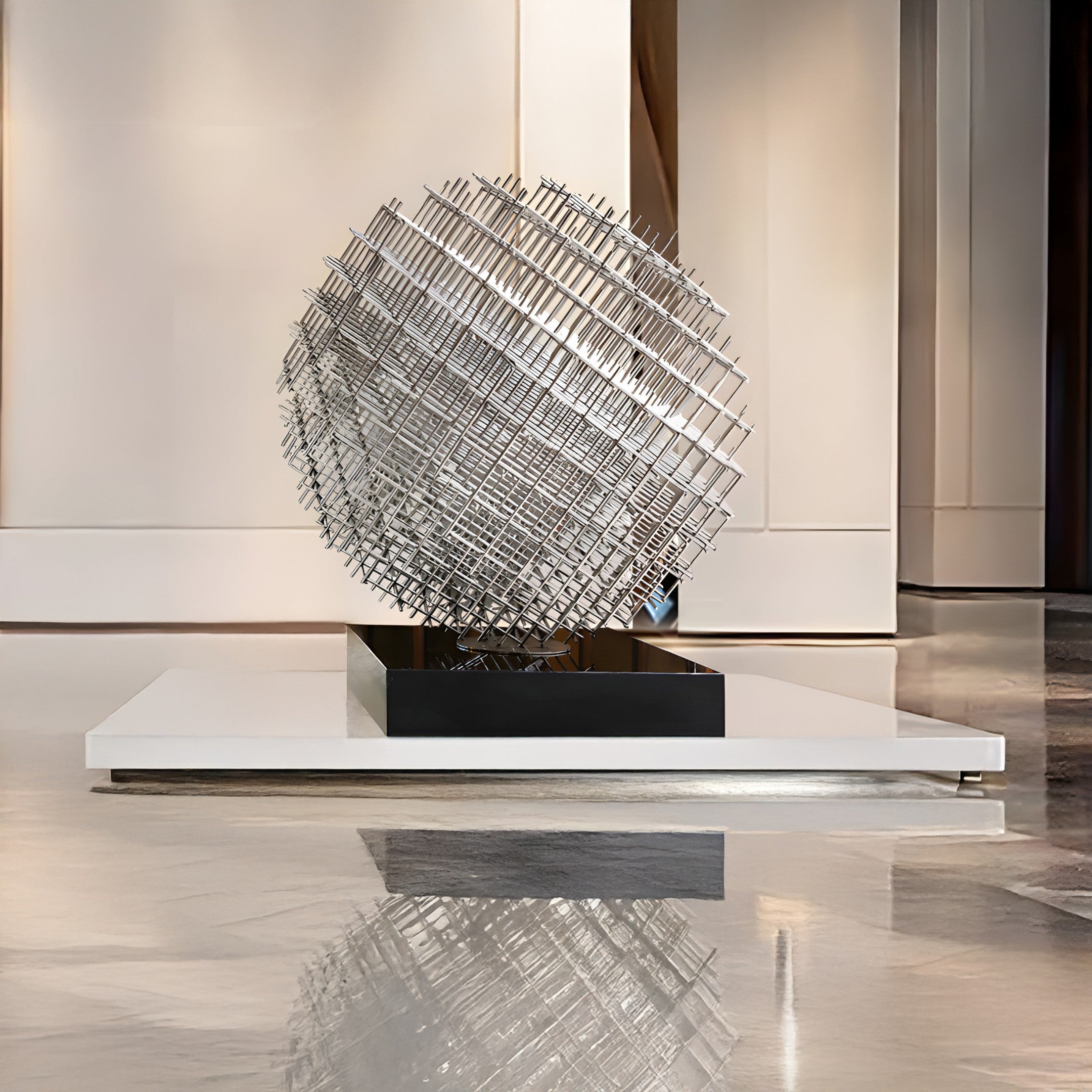 A Mesh Silver Geometric Steel Sculpture by Giant Sculptures, measuring 135/200cm, serves as the centerpiece of a modern art installation. It features intersecting metal rods elegantly displayed on a black and white platform within a gallery. The polished floor and neutral-colored walls accentuate the sleekness of the design.