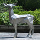 The "Deer II Geometric Steel Outdoor Sculpture - 160cm" by Giant Sculptures is positioned on a stone base amidst vibrant green vegetation. Its angular design lends a modern and abstract look to this outdoor artwork.