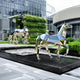 Outdoor setting of a silver geometric horse sculpture positioned next to a reflecting pool, with water ripples creating a dynamic effect in the sculpture's mirror-like surface.