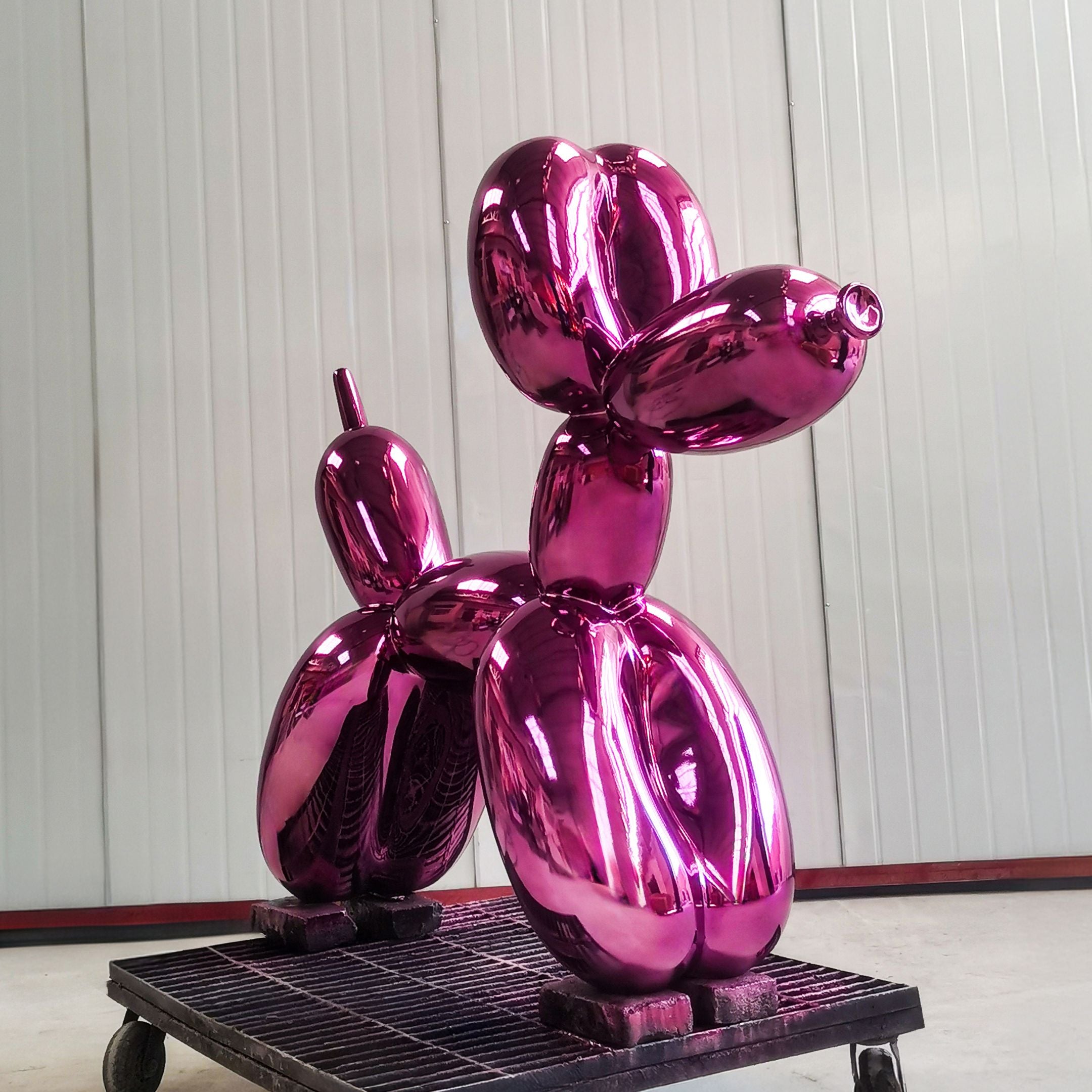 The Phantom Purple Balloon Dog Sculpture by Giant Sculptures, standing 80cm tall, is placed on a wheeled platform against minimalist white panel walls, reflecting light for a metallic look.